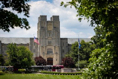 Burruss Hall in summer with a Blacksburg Transit bus passing in front of it.